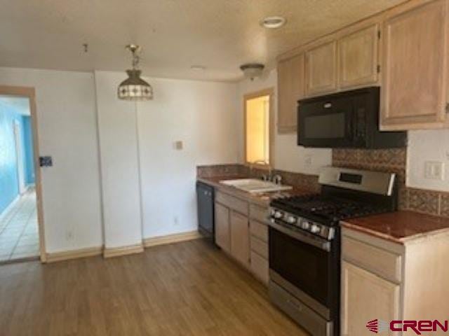 kitchen featuring black appliances, sink, decorative light fixtures, dark wood-type flooring, and light brown cabinets