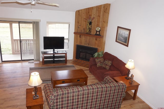 living room featuring a fireplace, light wood-type flooring, and ceiling fan