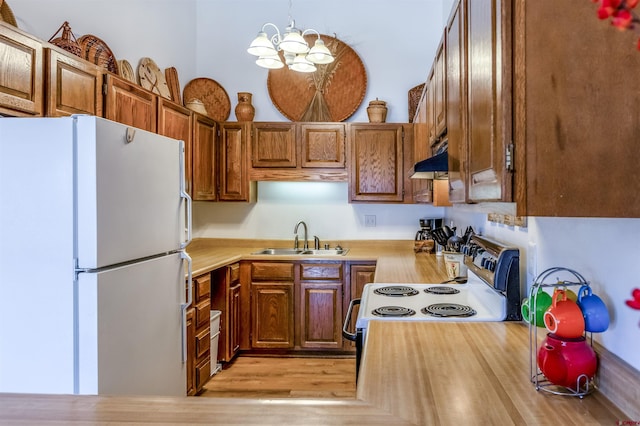 kitchen with sink, hanging light fixtures, an inviting chandelier, extractor fan, and white appliances