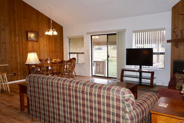 living room with dark hardwood / wood-style flooring, lofted ceiling, a notable chandelier, and wood walls