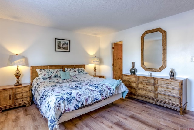 bedroom with a textured ceiling and light hardwood / wood-style floors