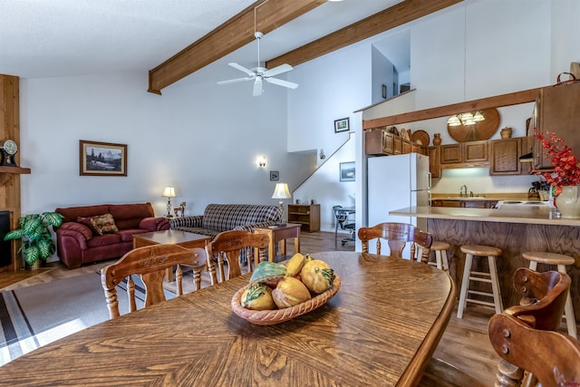 dining room with high vaulted ceiling, sink, light hardwood / wood-style flooring, ceiling fan, and beamed ceiling