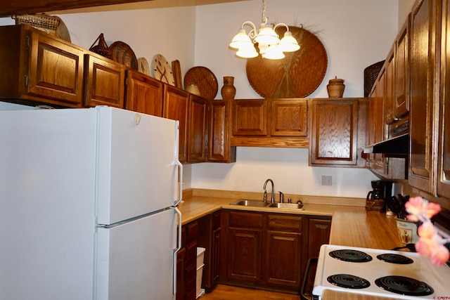 kitchen with a chandelier, sink, hanging light fixtures, and white appliances