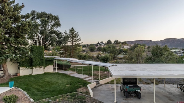 yard at dusk with a carport and a mountain view