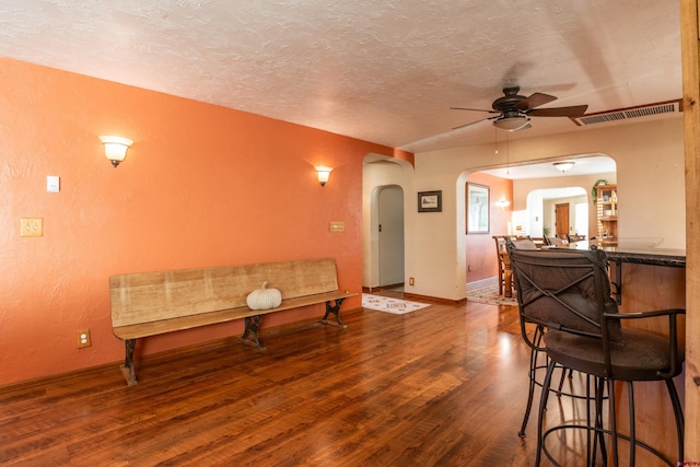 living room featuring a textured ceiling, wood-type flooring, and ceiling fan