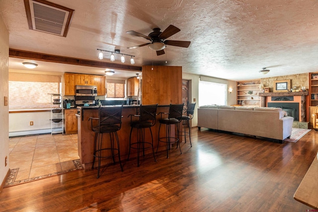 kitchen featuring a breakfast bar, a fireplace, kitchen peninsula, and hardwood / wood-style flooring