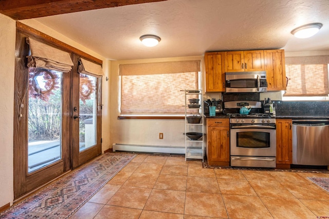 kitchen with a baseboard heating unit, appliances with stainless steel finishes, a textured ceiling, light tile patterned flooring, and french doors