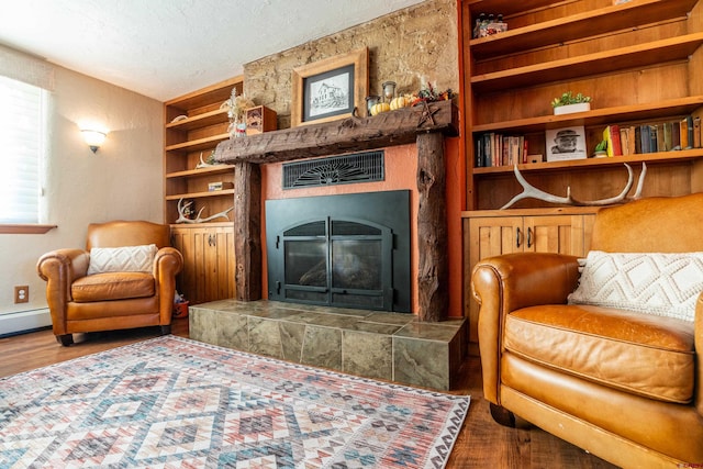 sitting room featuring a tiled fireplace, wood-type flooring, and a textured ceiling