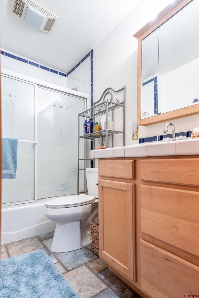 full bathroom with vanity, bath / shower combo with glass door, and toilet