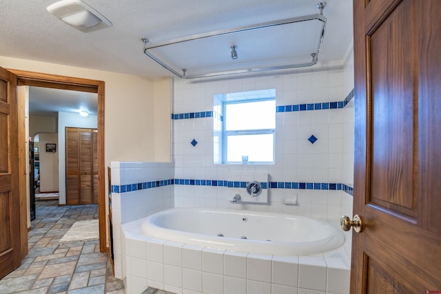 bathroom featuring a textured ceiling and tiled tub