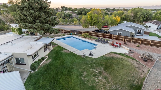 pool at dusk with a patio area and a yard