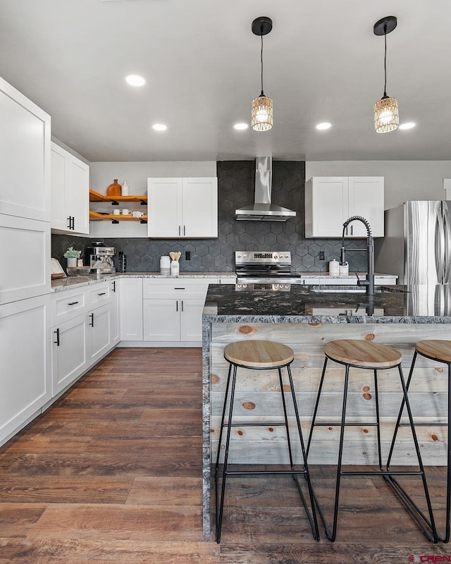 kitchen with white cabinetry, wall chimney exhaust hood, appliances with stainless steel finishes, and dark stone counters