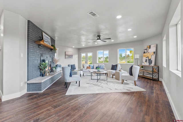 living room with french doors, ceiling fan, dark wood-type flooring, and a brick fireplace