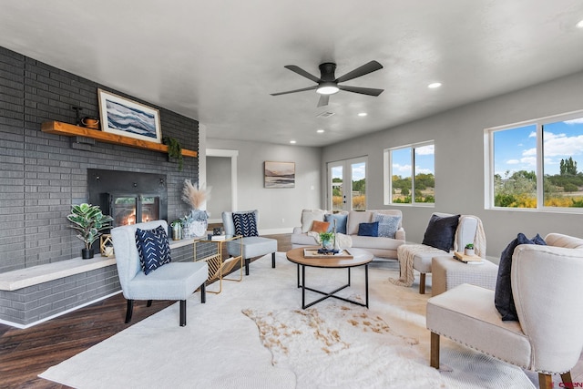 living room featuring ceiling fan, a brick fireplace, and hardwood / wood-style floors