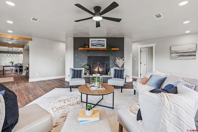 living room with a brick fireplace, wood-type flooring, and ceiling fan