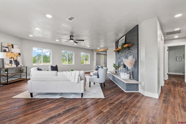 living room featuring dark hardwood / wood-style floors, ceiling fan, and a brick fireplace