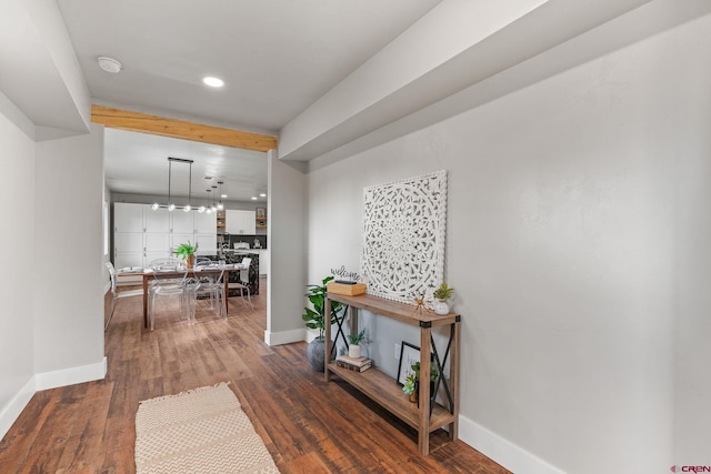 corridor featuring a notable chandelier, beam ceiling, and dark hardwood / wood-style flooring