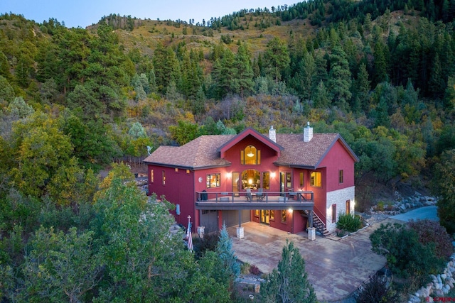 2239 Mockingbird Valley Ct, Durango, CO 81301 - view of front of house with a chimney, a view of trees, driveway, a carport, and stairway