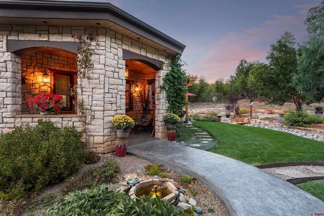 2239 Mockingbird Valley Ct, Durango, CO 81301 - exterior entry at dusk with stone siding and a lawn