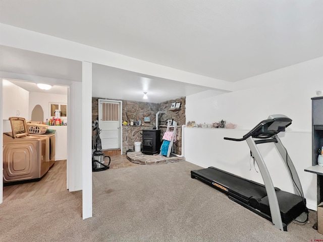 workout room with light colored carpet and a wood stove