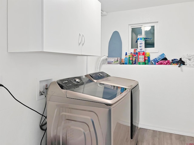 laundry area featuring hardwood / wood-style flooring, washing machine and dryer, and cabinets