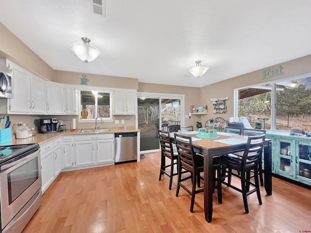 kitchen featuring sink, appliances with stainless steel finishes, white cabinetry, and plenty of natural light