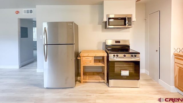 kitchen featuring appliances with stainless steel finishes, light hardwood / wood-style flooring, and wood counters