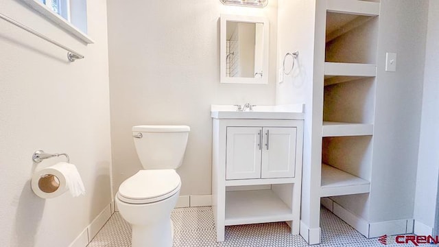 bathroom with toilet, vanity, and tile patterned floors