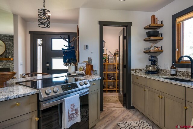 kitchen featuring hanging light fixtures, sink, light stone countertops, stainless steel range with electric cooktop, and light hardwood / wood-style floors