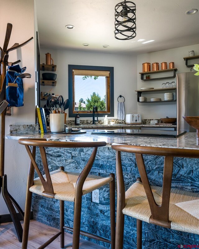 bar with stainless steel refrigerator and hardwood / wood-style floors