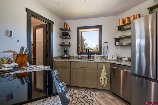 kitchen with light hardwood / wood-style flooring, light stone counters, stainless steel appliances, and sink