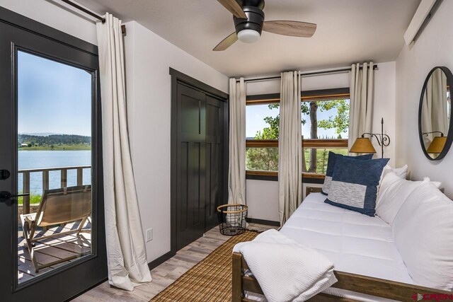 interior space featuring multiple windows, a water view, light hardwood / wood-style floors, and ceiling fan