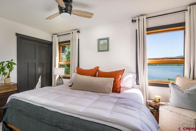 bedroom with a water view, ceiling fan, a closet, and wood-type flooring