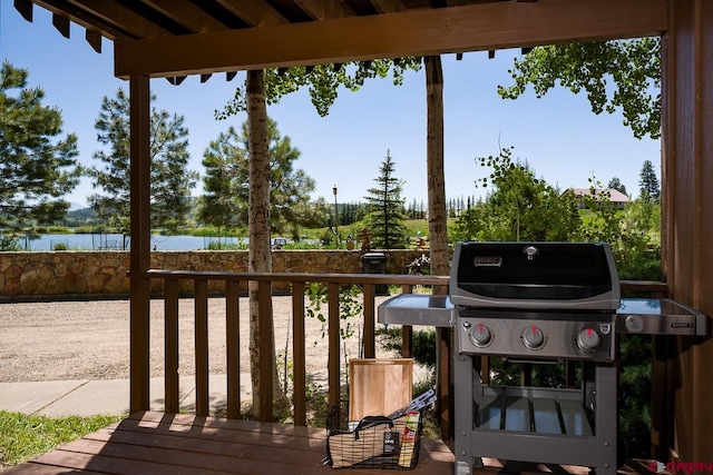 wooden terrace featuring a grill and a water view