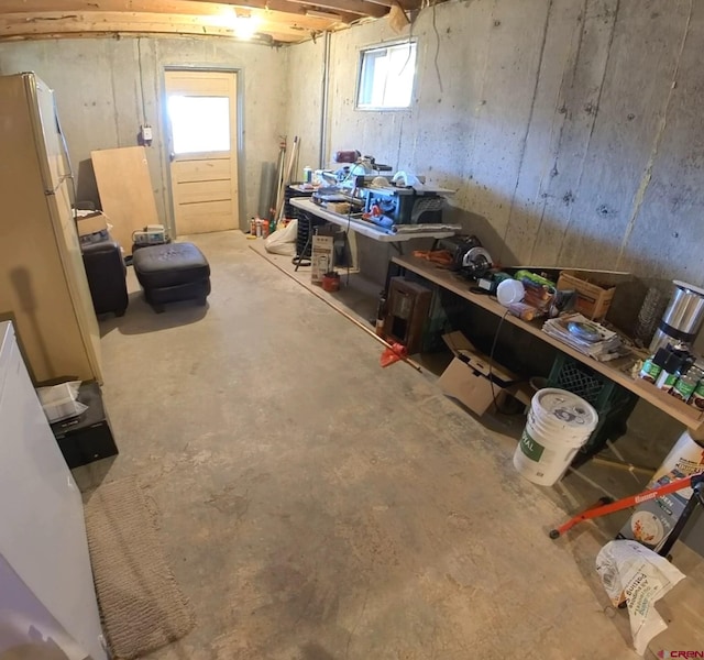 basement with white fridge and a healthy amount of sunlight