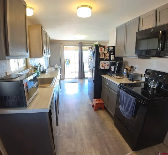 kitchen with a healthy amount of sunlight, black appliances, and light wood-type flooring