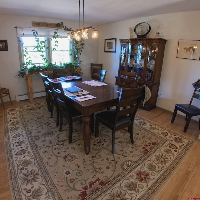 dining room featuring baseboard heating, light hardwood / wood-style flooring, and a notable chandelier