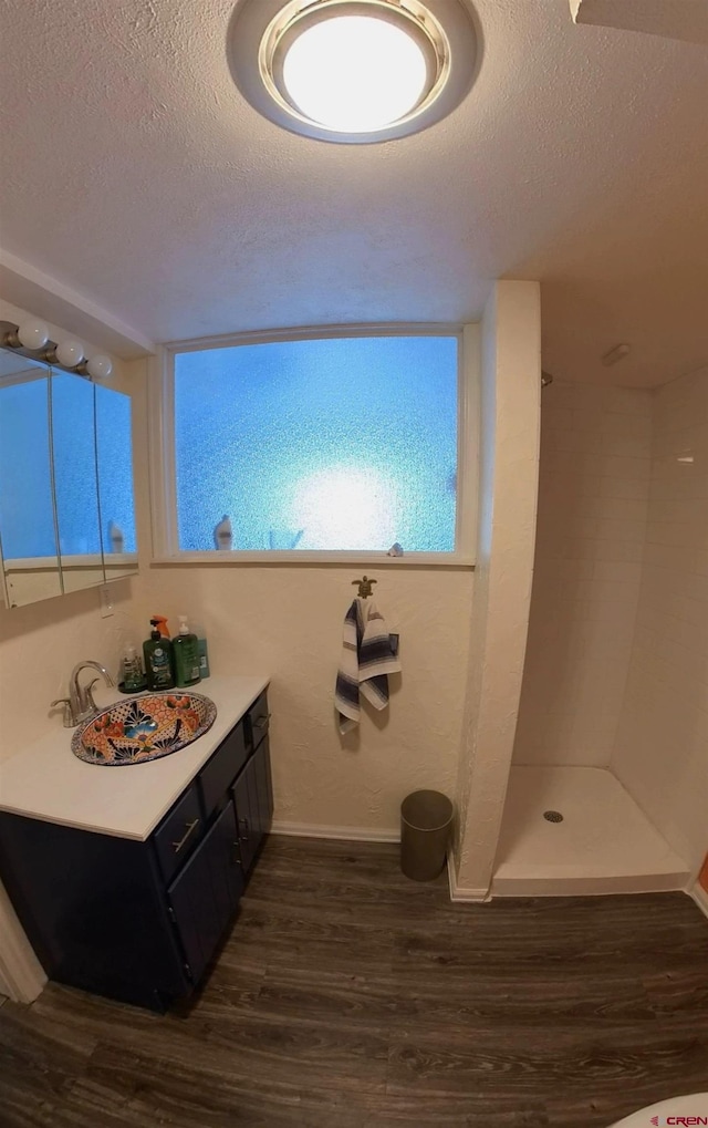 bathroom with vanity, hardwood / wood-style flooring, a textured ceiling, and walk in shower