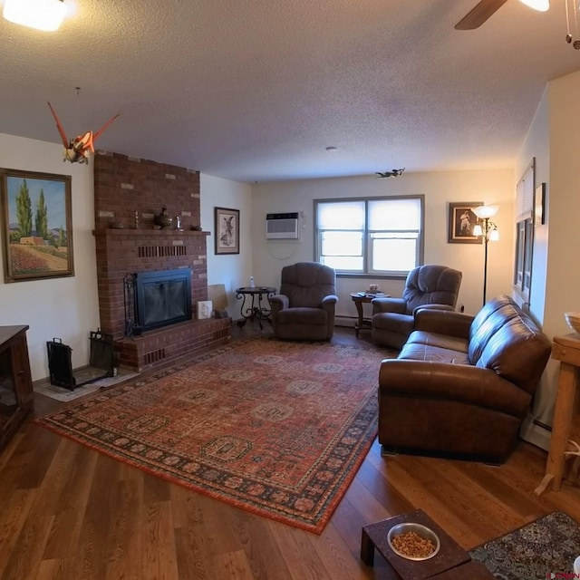 living room featuring an AC wall unit, a textured ceiling, a brick fireplace, and hardwood / wood-style floors