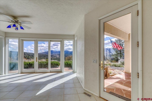 doorway with a mountain view, a textured ceiling, plenty of natural light, and ceiling fan