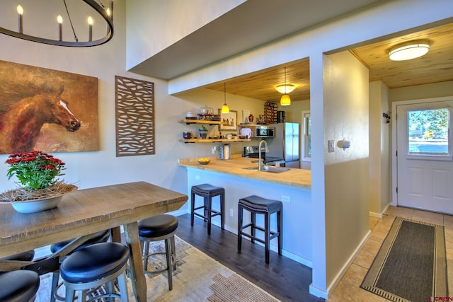 kitchen with sink, wood ceiling, a kitchen breakfast bar, pendant lighting, and hardwood / wood-style flooring