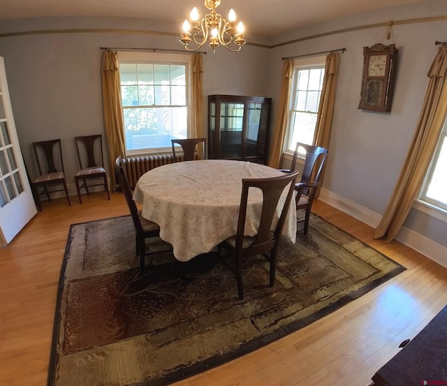 dining area with light hardwood / wood-style floors and an inviting chandelier