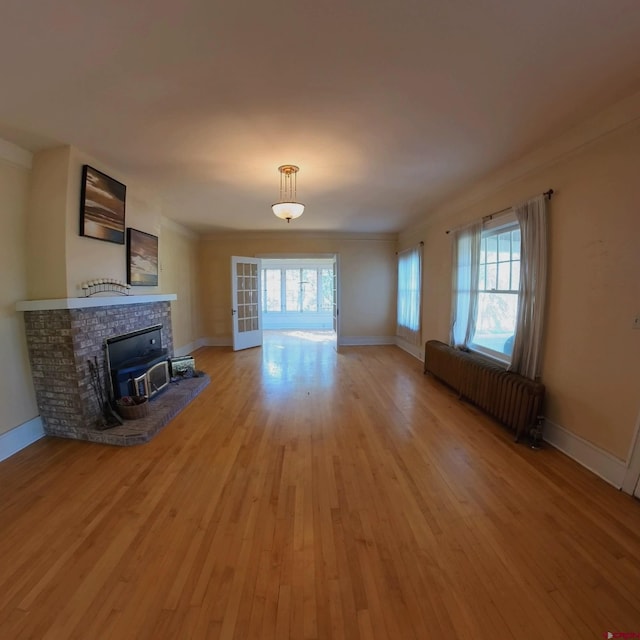 unfurnished living room with radiator, a healthy amount of sunlight, and light wood-type flooring