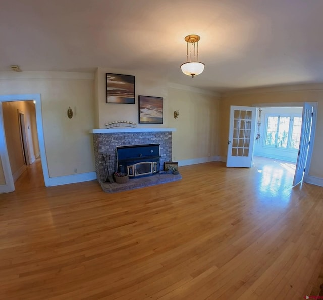 unfurnished living room with a stone fireplace, light hardwood / wood-style flooring, french doors, and crown molding