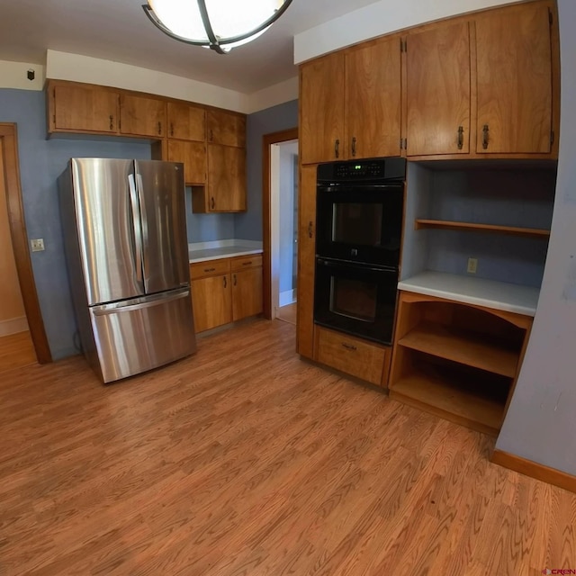 kitchen with light hardwood / wood-style flooring, double oven, and stainless steel refrigerator