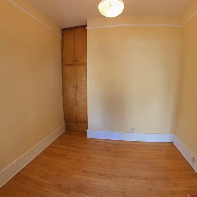 empty room featuring ornamental molding and light hardwood / wood-style floors