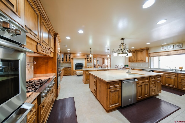 kitchen featuring hanging light fixtures, backsplash, an island with sink, stainless steel appliances, and sink