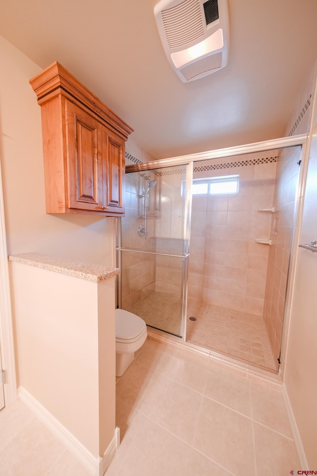 bathroom with tile patterned floors, a shower with shower door, and toilet