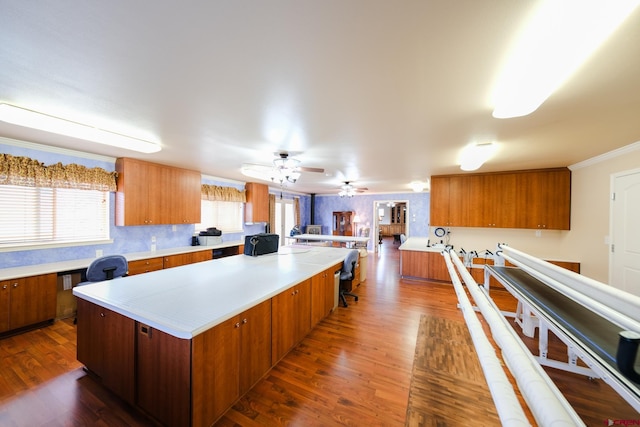 kitchen featuring dark wood-type flooring, a healthy amount of sunlight, ornamental molding, and a kitchen island