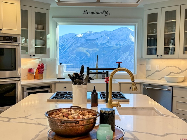 kitchen featuring backsplash, stainless steel appliances, a mountain view, and light stone counters